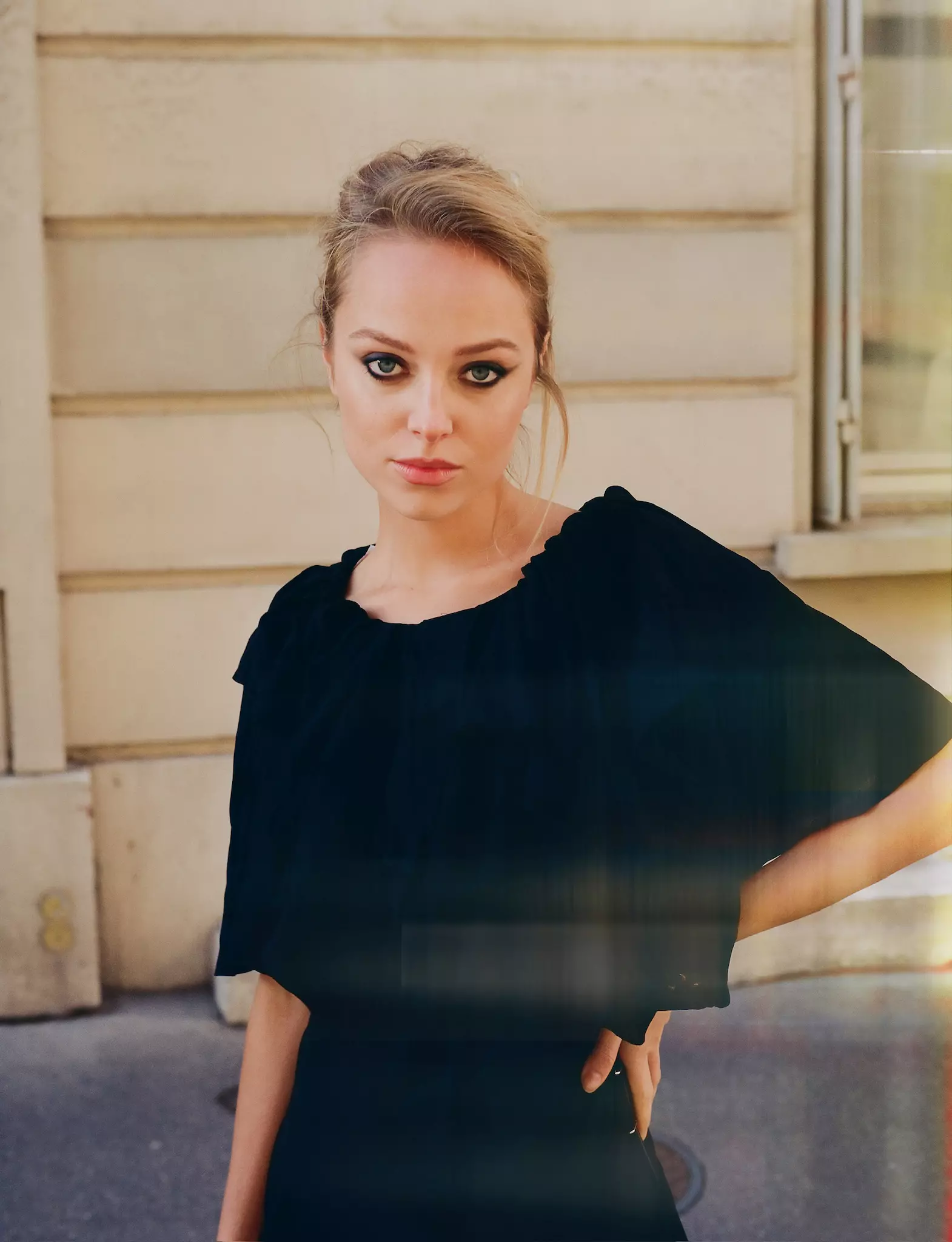 Model in black top featuring bold eye makeup and textured updo hairstyle created by Mandy Dorian