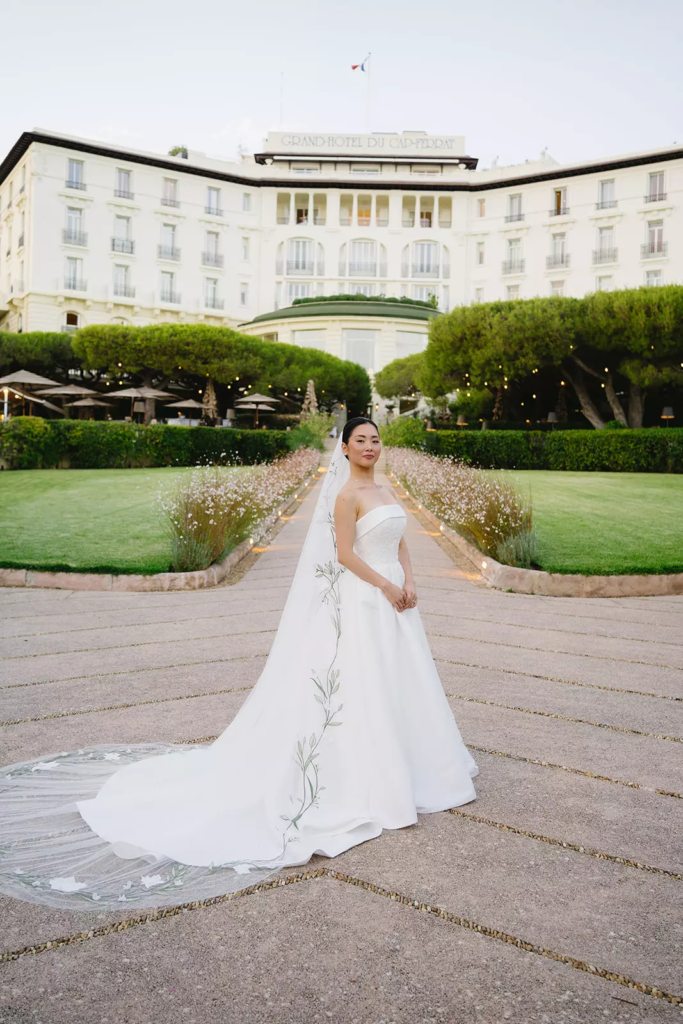 Bride standing in front of Four Seasons Cap-Ferrat wearing refined bun hairstyle and soft natural makeup