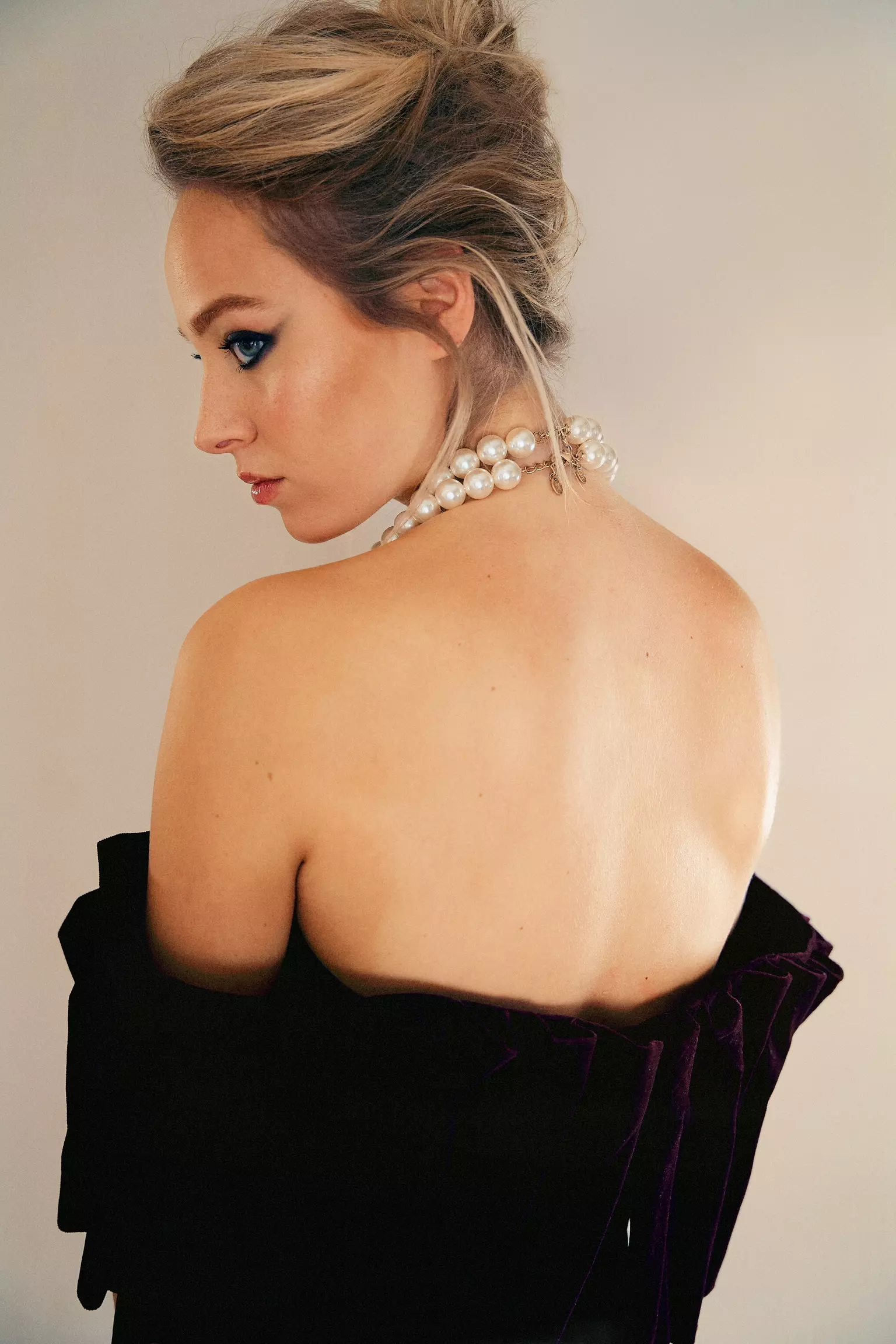 Back view of model with elegant updo hairstyle and pearl necklace for L’Officiel fashion editorial
