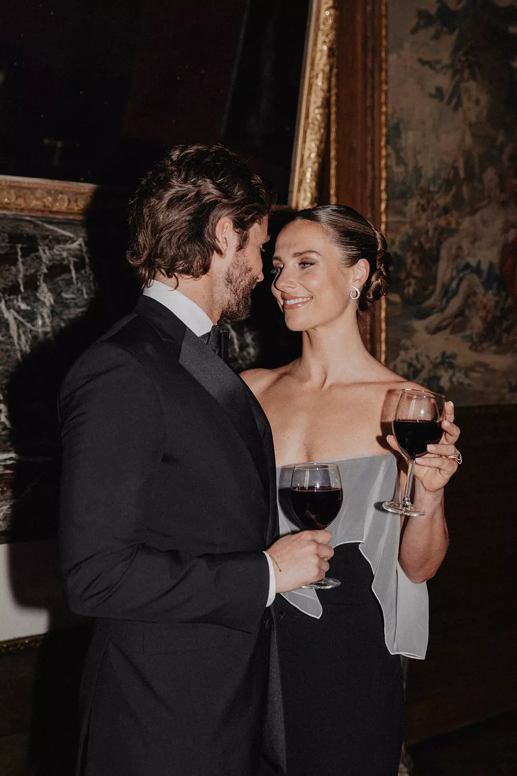 Bride holding wine glass with flawless skin finish and sculpted bridal hairstyle