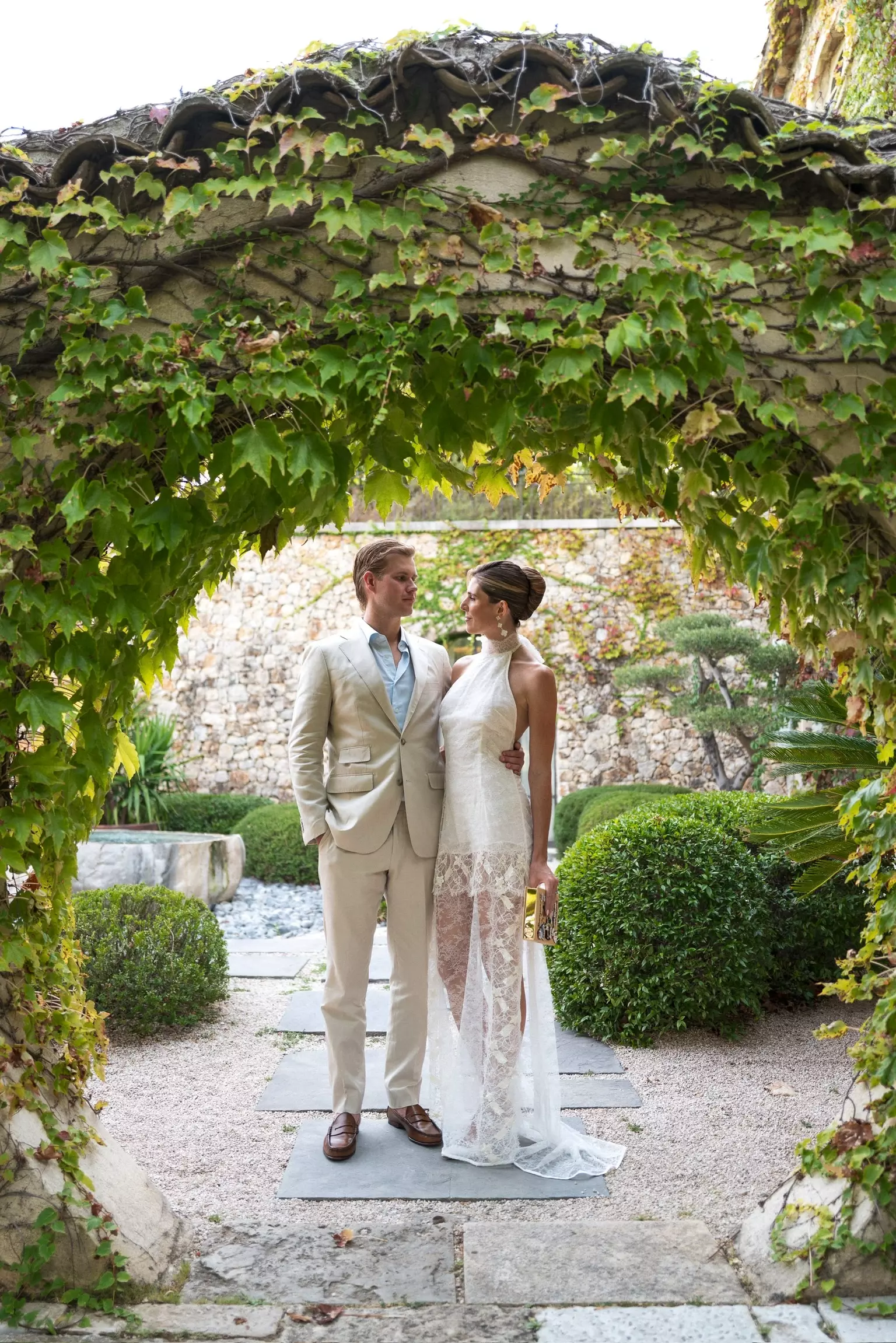 Bride and groom walking through château gardens showcasing elegant bridal styling by Mandy Dorian