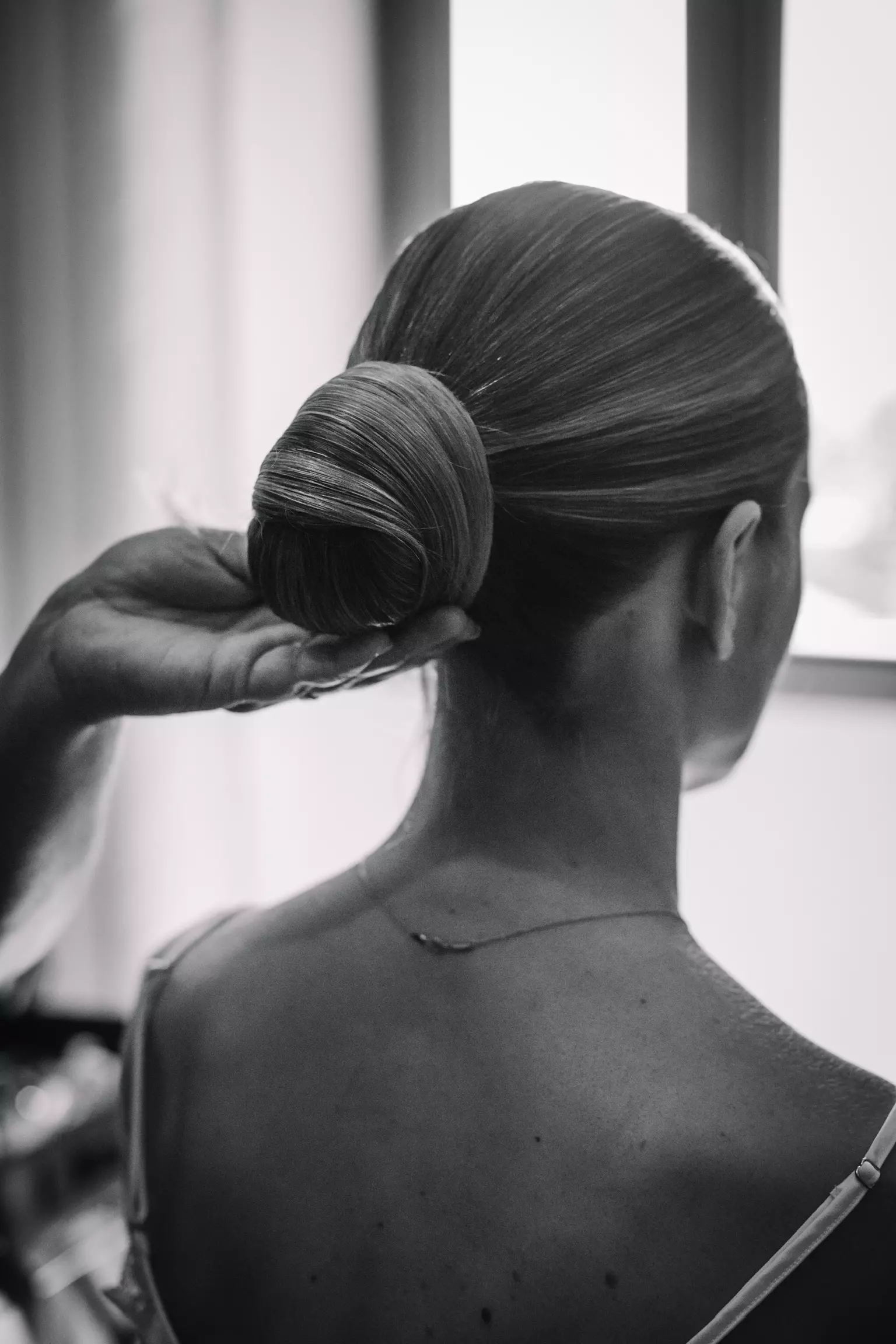 Close up black and white portrait of sleek bridal low bun showcasing precision hairstyling expertise