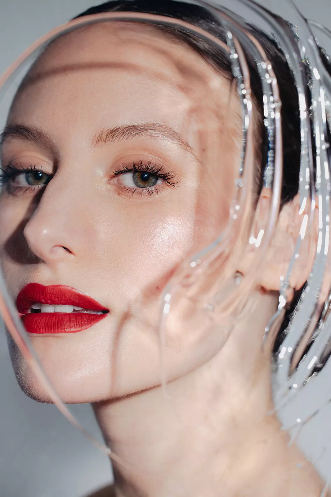 Close up of model with bold red lipstick and radiant skin finish showcasing makeup artistry