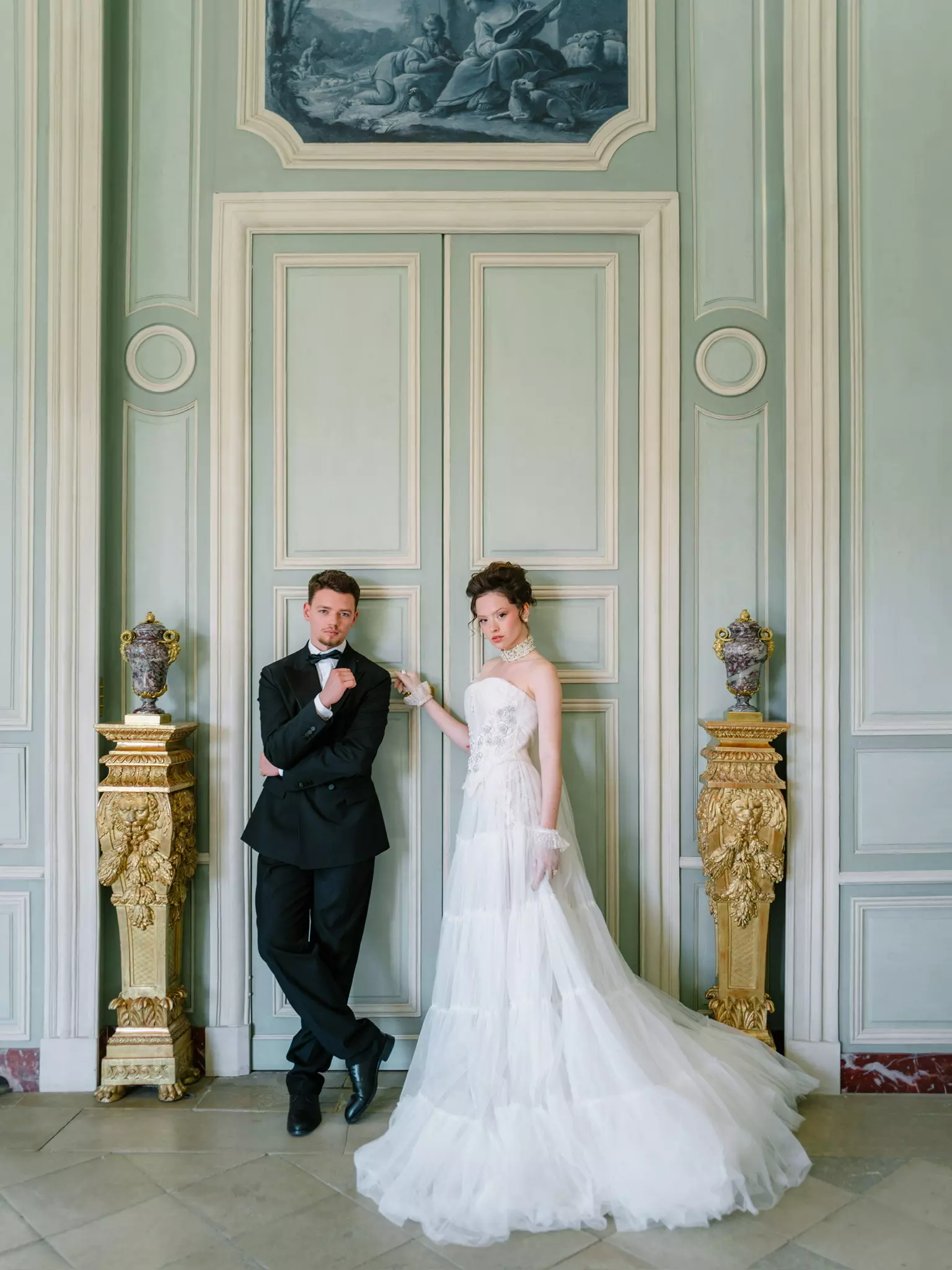 Bride and groom posed in grand château doorway with polished bridal beauty by Mandy Dorian