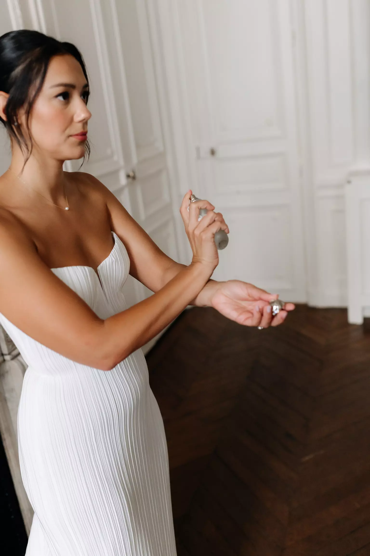 Bride applying perfume with soft refined bridal makeup and smooth complexion finish