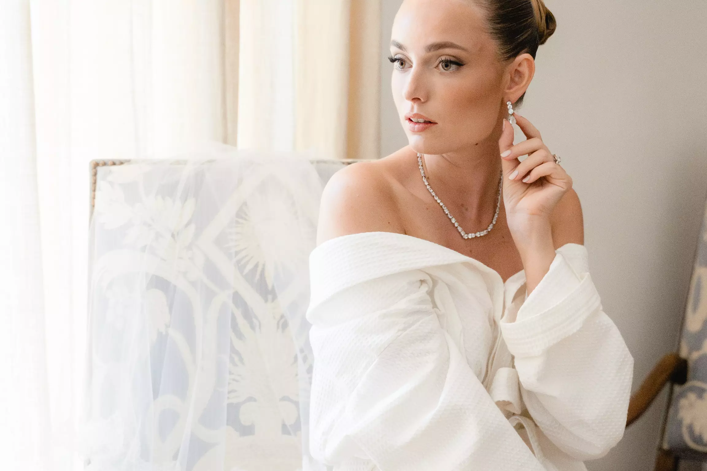 Bride Joan wearing off-shoulder gown with polished bridal bun and luminous complexion in Saint-Tropez