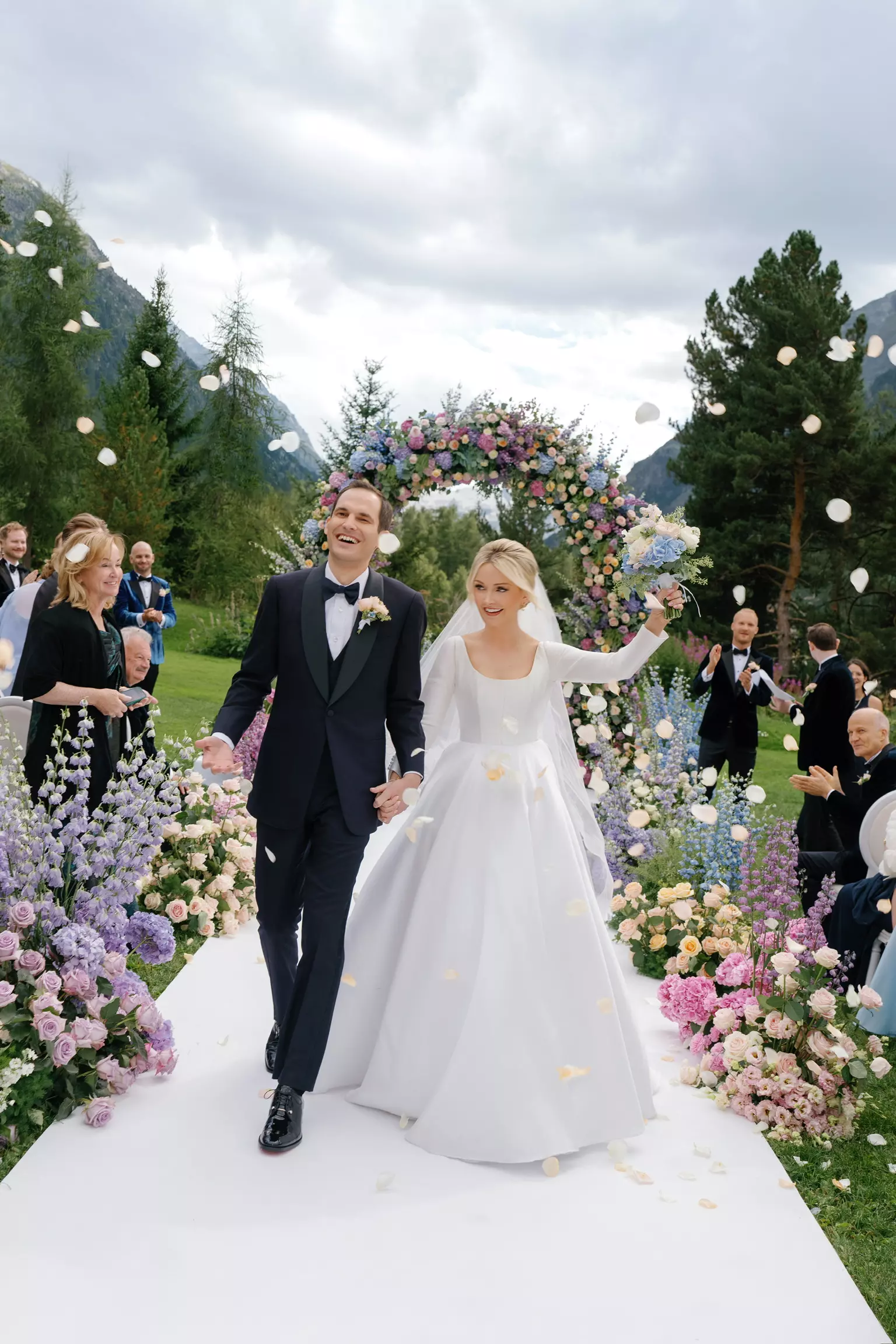 Bride and groom walking under floral arch after ceremony with refined bridal beauty by Mandy Dorian