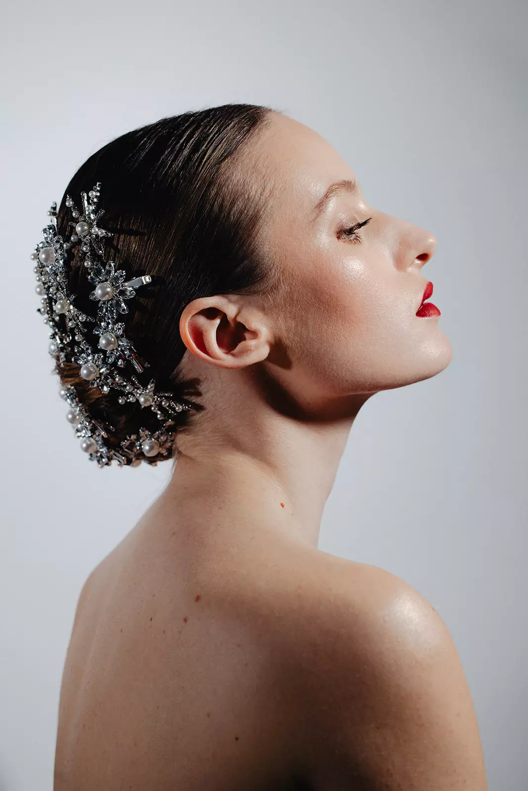 Model wearing crystal hair accessory with glossy red lip and precision editorial makeup