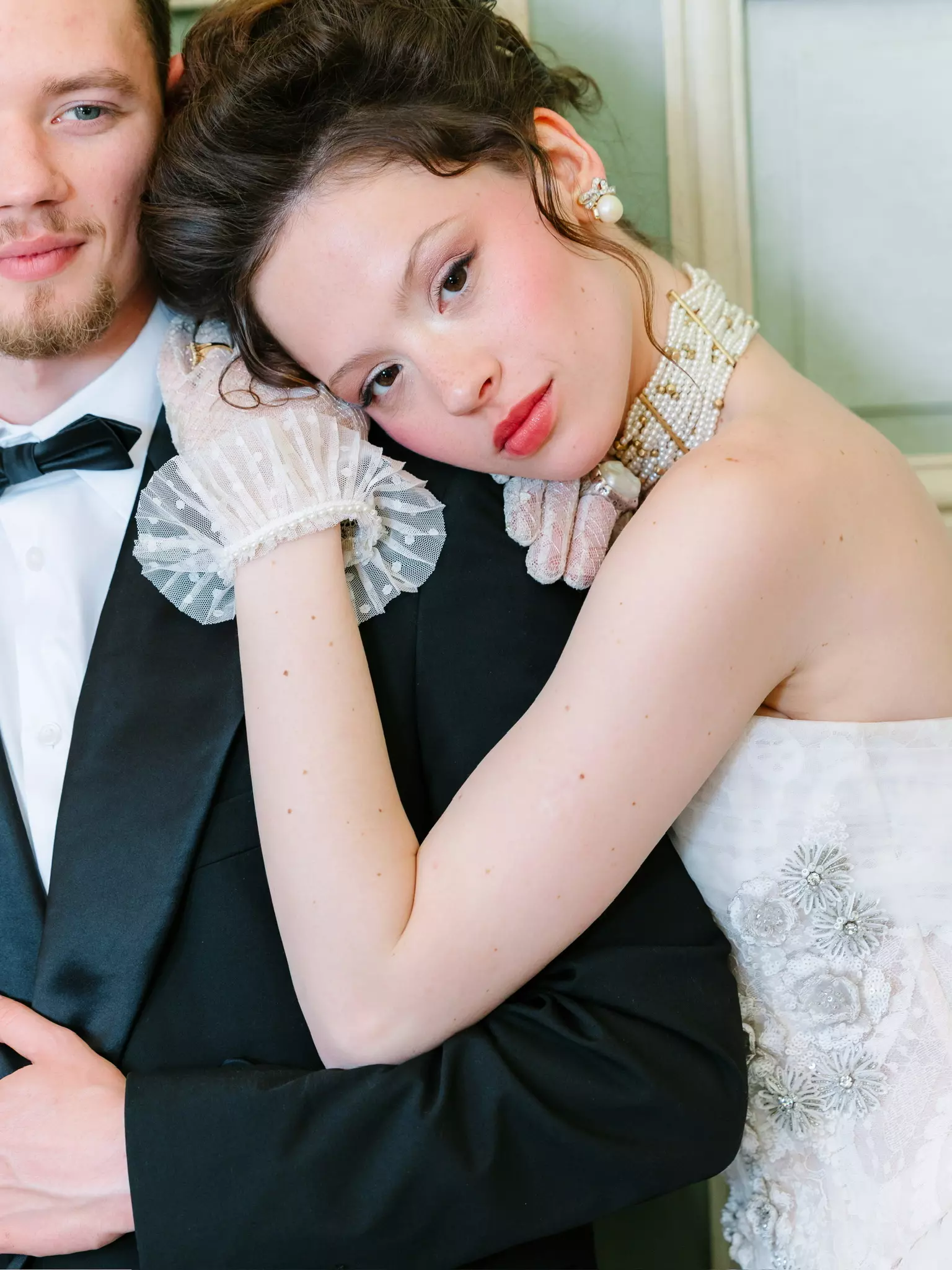 Bride resting on groom’s shoulder featuring modern romantic bridal makeup and elegant hairstyle