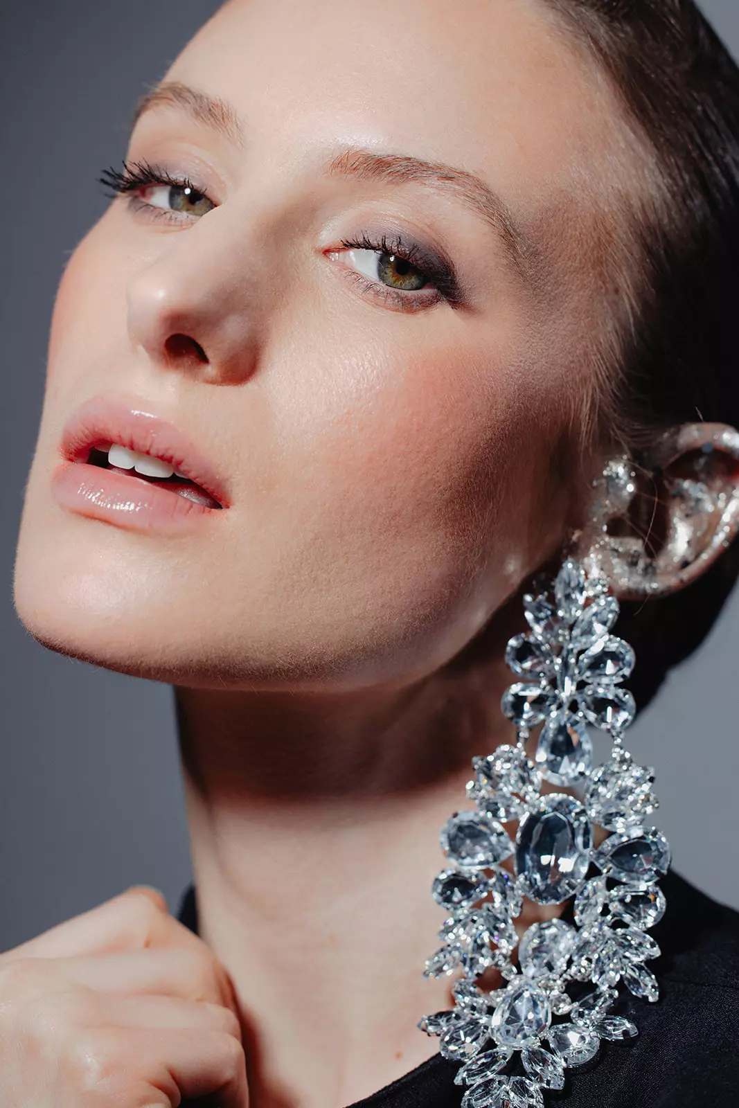 Model with luminous skin and bold red lips wearing crystal statement earrings styled by Mandy Dorian