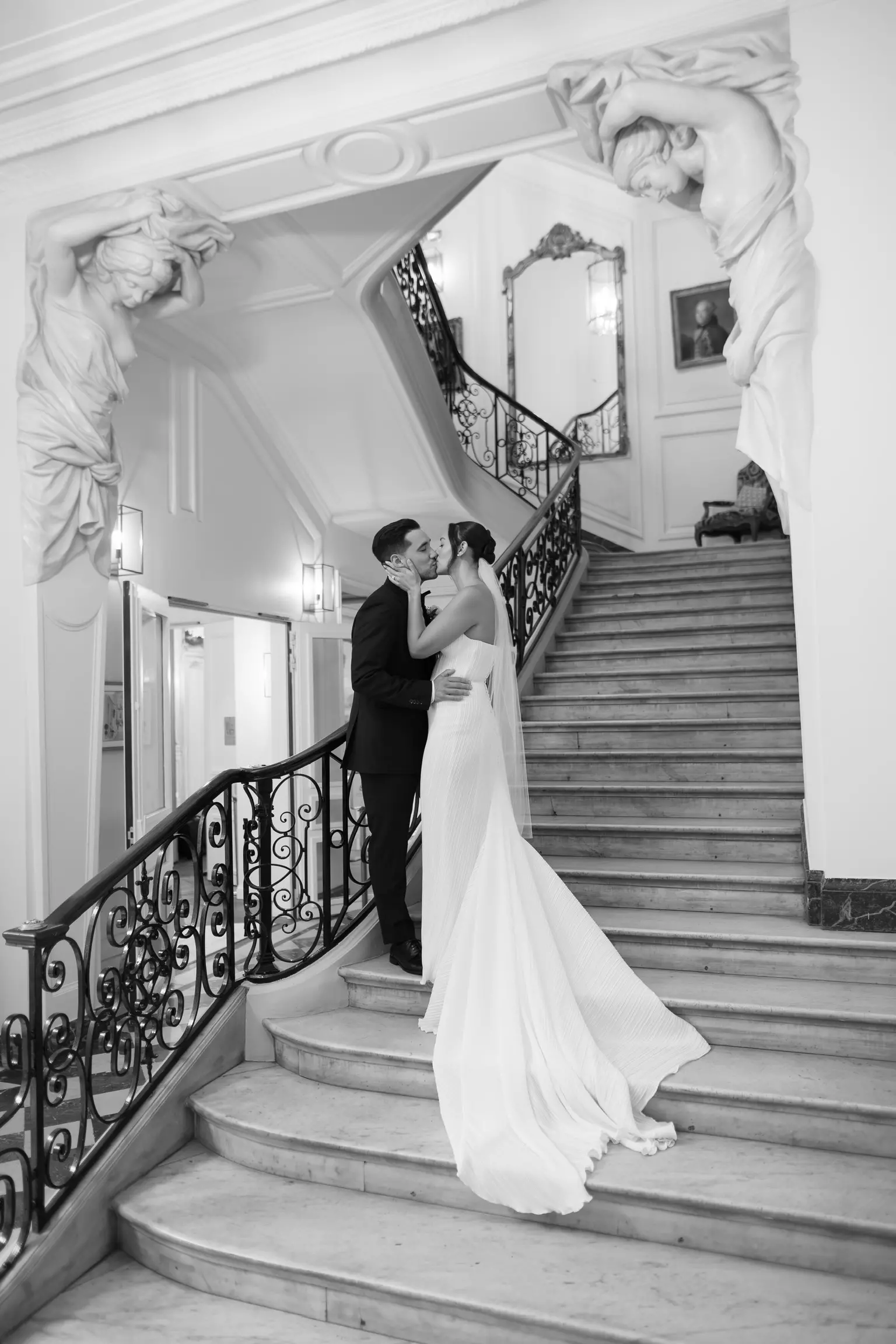 Bride and groom embracing on staircase with precision bridal hairstyle and elegant makeup styling