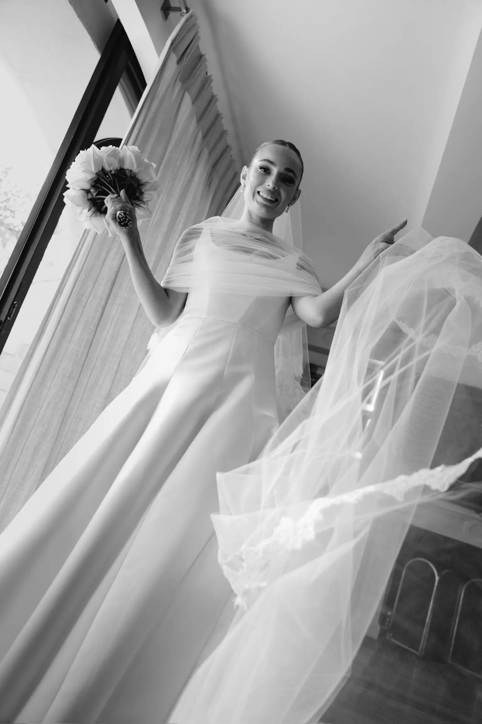 Bride holding veil during ceremony featuring structured bridal bun and soft natural makeup