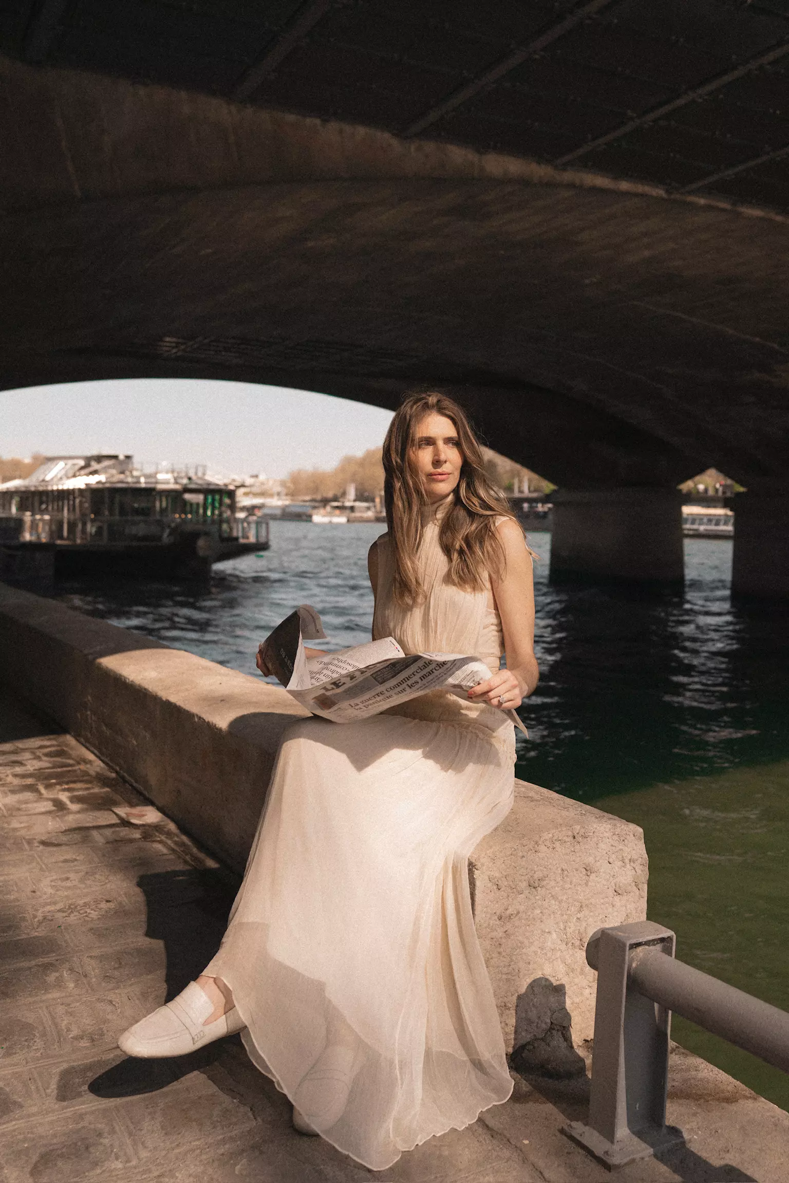 Bride seated by the Seine during luxury bridal trial photoshoot featuring polished hair and makeup styling
