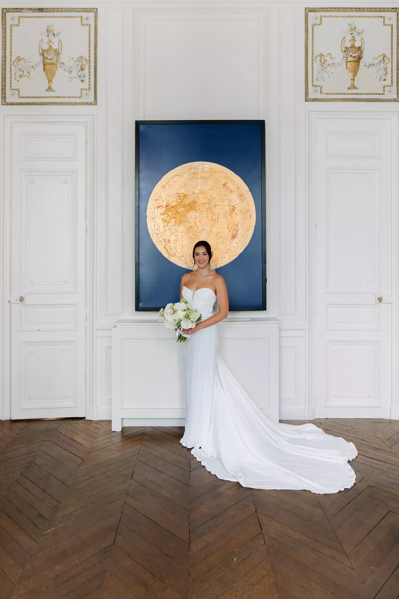 Bride standing in Parisian interior featuring refined bridal bun and natural radiant makeup by Mandy Dorian