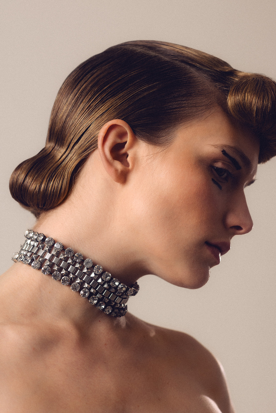 Close up profile highlighting luminous skin finish and sculpted low bun hairstyle by Mandy Dorian