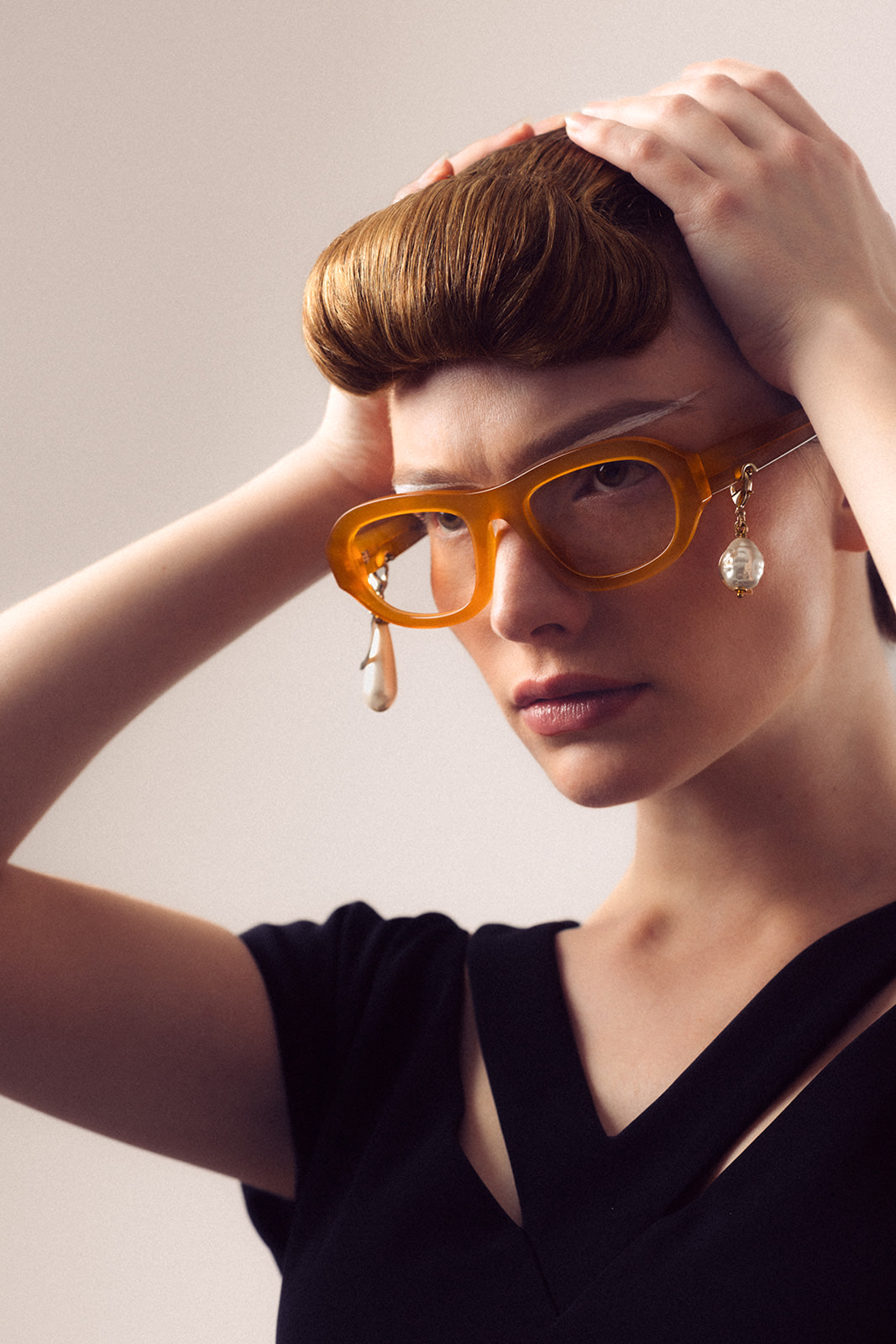 Model wearing orange glasses showcasing precise complexion work and structured hairstyling