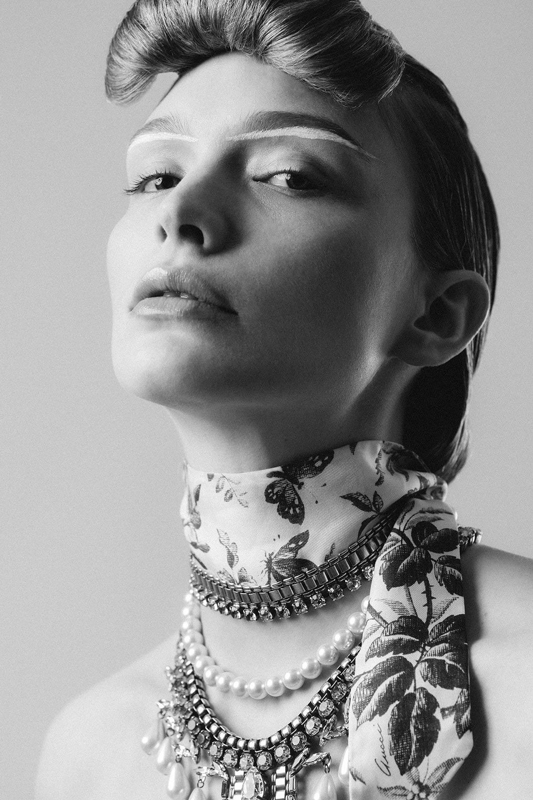 Black and white portrait highlighting precise editorial makeup and sleek structured hairstyle