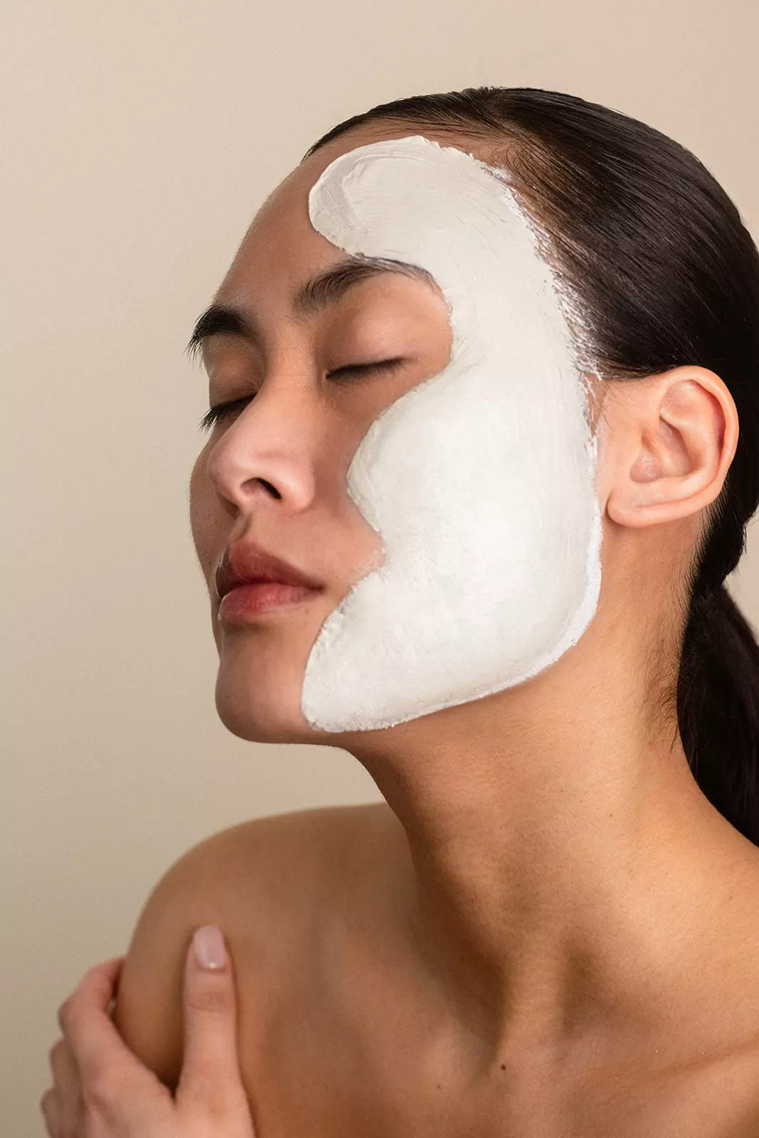 Model applying white facial mask highlighting skin preparation and beauty expertise by Mandy Dorian