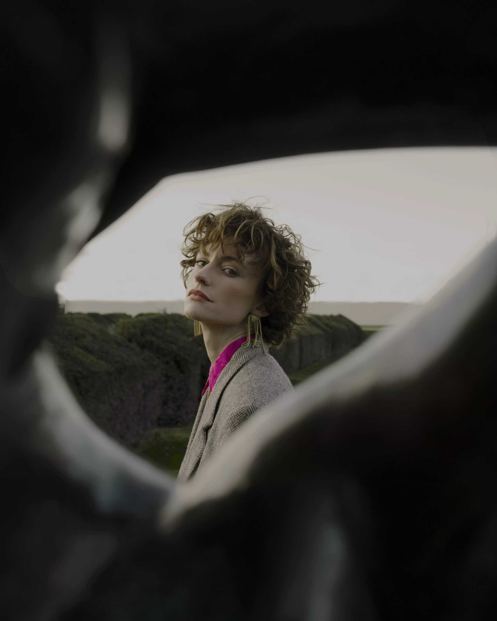 Model framed through circular foreground with bold editorial makeup and modern styling